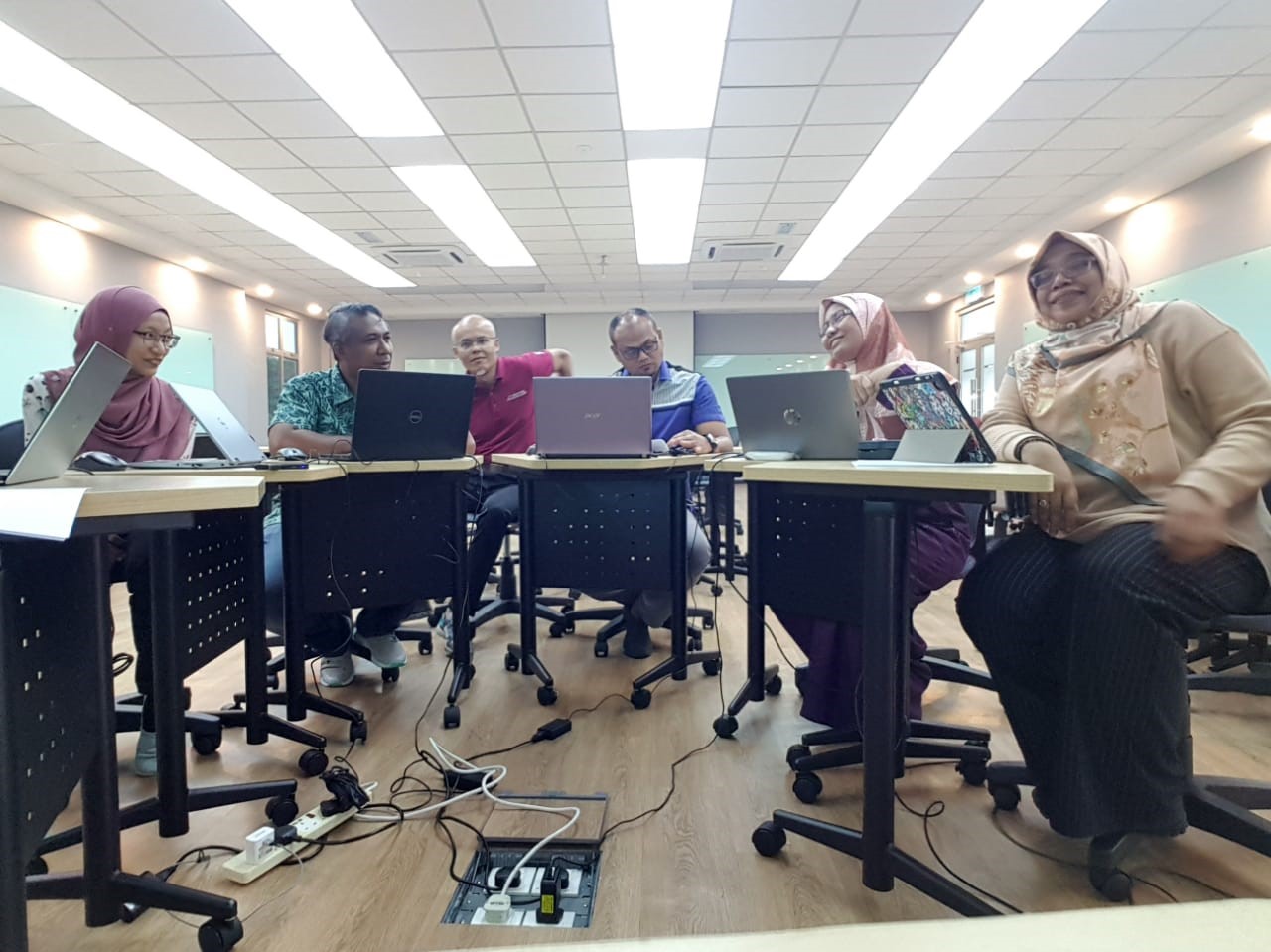 A group of people sitting at desks with laptops Description automatically generated with medium confidence