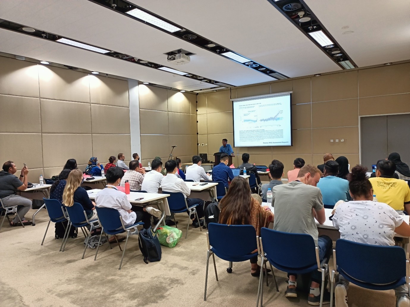 A group of people sitting in a room looking at a screen Description automatically generated with medium confidence